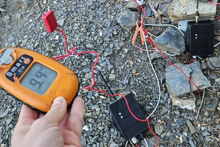 Testeur de clôture affichant 9,9 kV à côté des capteurs